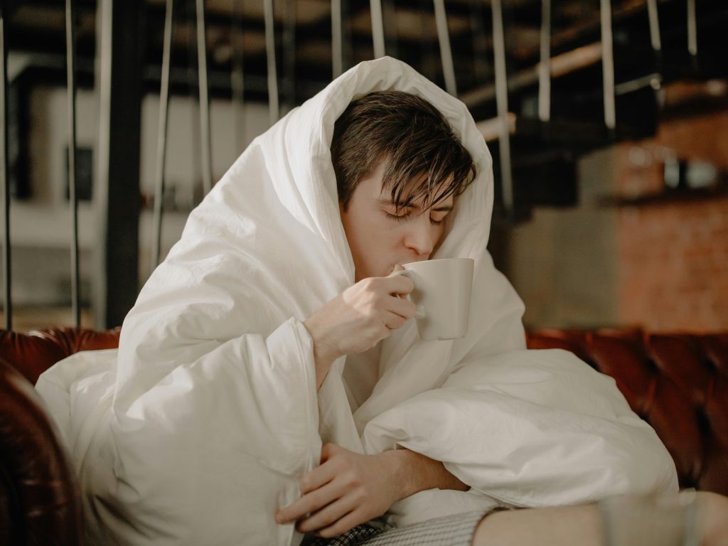 Person sipping tea while under a blanket